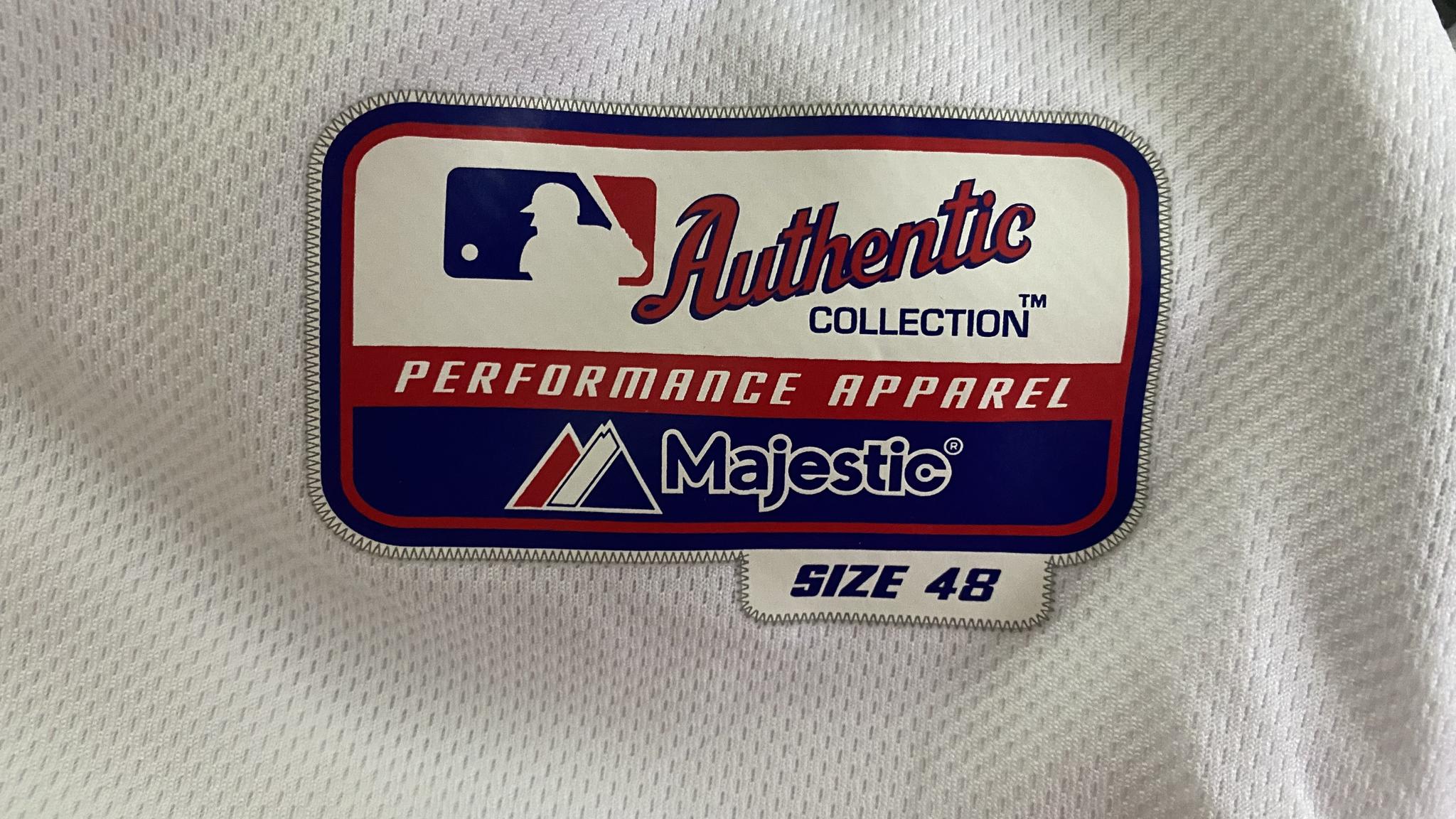An image of the tag featured on an Authentic MLB jersey. It features the MLB logo and the words "Authentic Collection/Performance Apparel/Majestic/Size 48"